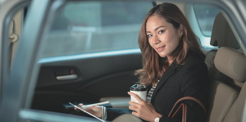 Attractive businesswoman working on the car with a cup of coffee while heading to office