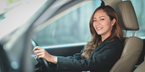 Beautiful professional businesswoman smiling at the camera while driving the car to the office