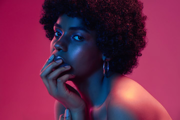 Summer's sunset. Portrait of female fashion model in neon light on gradient background. Beautiful...