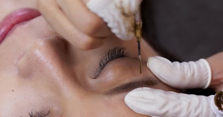Asian woman having microblading eyebrows in a beauty salon