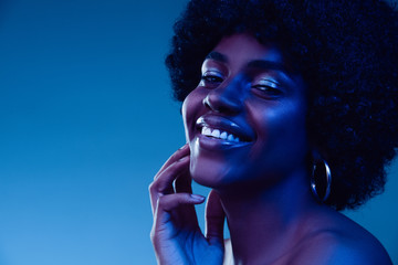 Marvelous night. Portrait of female fashion model in neon light on gradient background. Beautiful african woman with trendy make-up and well-kept skin. Vivid style, beauty, cosmetics concept.
