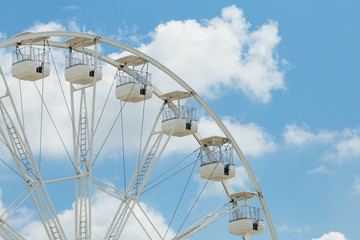 Ferris wheel on the blue cloudy sky. Background concept of happy holidays time.
