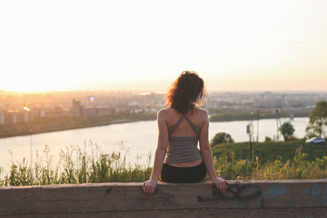 woman in T-shirt sitting in park at sunset,