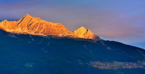beautiful orange mountain at sunset above alpine village