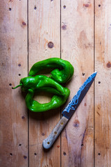 GREEN PEPPERS WITH KITCHEN KNIFE ON WOODEN TABLE. RUSTIC FOOD PHOTOGRAPHY