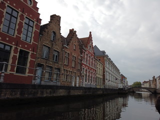 Fototapeta na wymiar Bruges, Belgium - May 2019: View of the water channel in the city center. Boat trip along the water canals of the city.