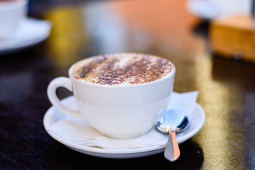 A cup of cappuccino coffee on a restaurant table, close up.
