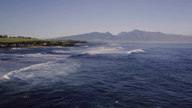 Reverse Fly Over Of Surfers And Mountains At A Tropical Island