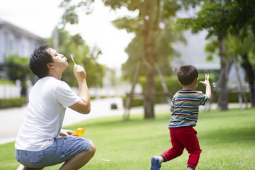 Fototapeta premium Father and son making soap bubbles in the park of village. Concept of friendly family.