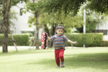Fototapeta premium Son playing with toy car and run in the garden at home having fun together and happy.