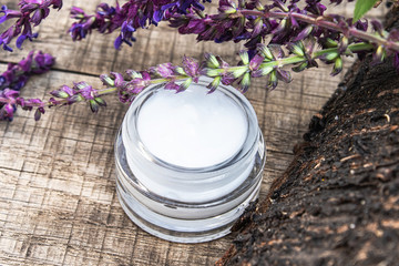 Obraz na płótnie Canvas Natural face cream with blue lavender wildflowers on a wooden background. Face cream.