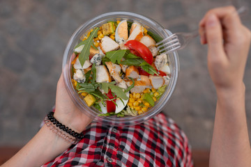 POV woman eating salad at urban city outdoor, dinner snack