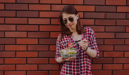 Young woman eating salad at urban city outdoor, dinner snack