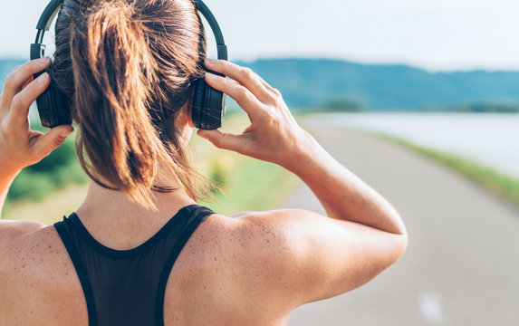 Close up image of teenager adjusting  wireless headphones before starting jogging and listening to music
