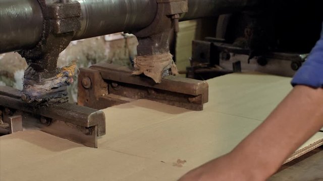 Closeup shot of a worker working on a cardboard slitting machine. 