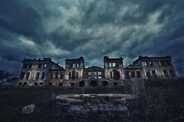 Old abandoned ruins and an old ruined fountain against a gloomy ominous sky.