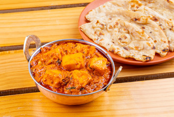Indian Delicious Spicy Vegetarian Cuisine Paneer Toofani Also Know as Paneer Tufani, Toofani Paneer Masala or Dhaba Style Paneer Masala Served with Tandoori Roti on Wooden Yellow Background