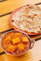 Indian Delicious Spicy Vegetarian Cuisine Paneer Toofani Also Know as Paneer Tufani, Toofani Paneer Masala or Dhaba Style Paneer Masala Served with Tandoori Roti on Wooden Yellow Background