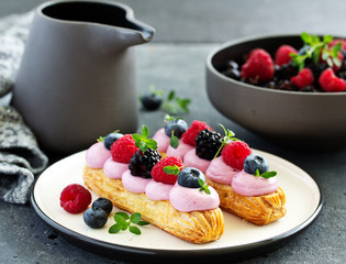 Homemade eclair with berry cream and fruits. . Pastry.