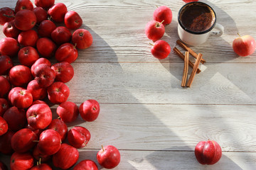 Red apples, rough cup of coffee and cinnamon sticks on white wooden boards or desk. Top view. Autumn, fall, morning, breakfast, healthy food concept