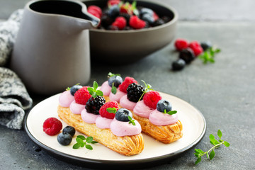 Homemade eclair with berry cream and fruits. . Pastry.