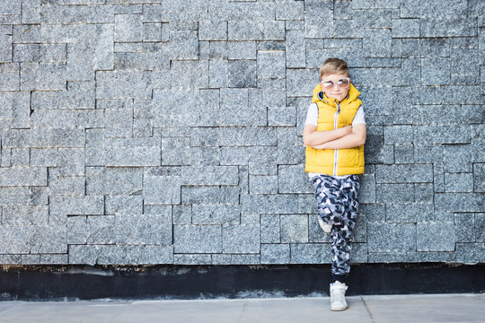 Cool Kid With Arms Crossed Wearing Sunglasses And Leaning On A Wall. Copy Space.