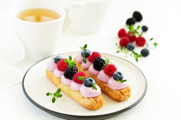 Homemade eclair with berry cream and fruits. . Pastry.
