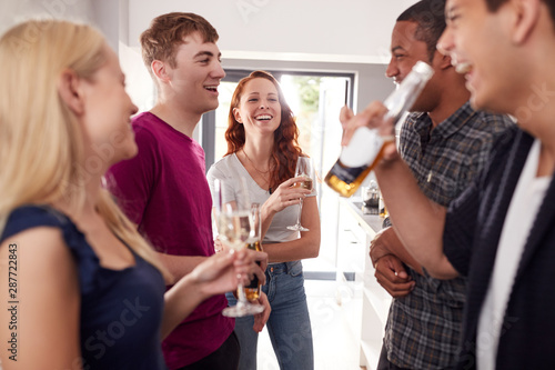 Group Of College Students In Shared House Kitchen Hanging Out And Drinking Together