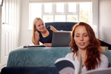 Two Female College Students In Shared House Bedroom Studying Together