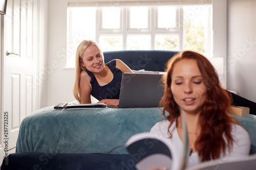 Two Female College Students In Shared House Bedroom Studying Together