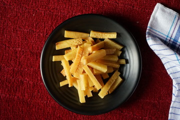 Crunchy fried of Breadfruits set on the black bowl, photographed on the red background.