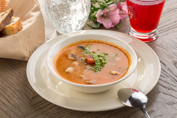 Hot and sour soup Tom Yum Goong with tomatoes and champignon and red drink on wooden table