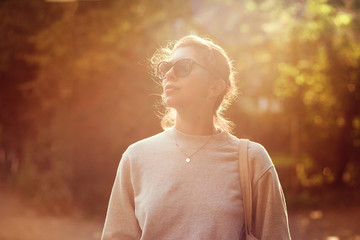 Beautiful young woman in sunglasses in autumn Park at sunset.