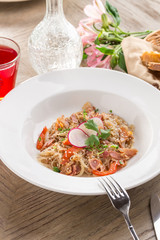 Delicious asian rice noodles with vegetables and bacon and red drink on wooden table
