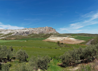 Fototapeta na wymiar The Limestone cliffs and mountains of the El Torcal Mountain range overlooking the Hill farms and fields in the valley below. Andalucia, Spain.