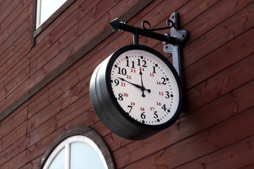Fototapeta na wymiar vintage vintage clock with a round dial hang on a wooden wall at the railway station. Reconstruction of the old station. Arrival and departure trains concept