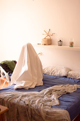 ghost sitting on the edge of a bed that is undone