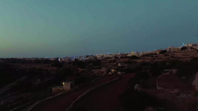 night aerial shot approaching Zurrieq village, Malta, flyover the terraced agricultural fields