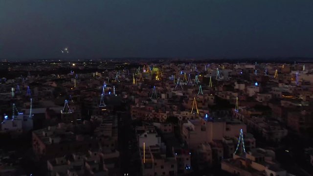 night aerial shot approaching Zurrieq village, Malta, Zoom in shot over the colorful decoration lights for village fest
