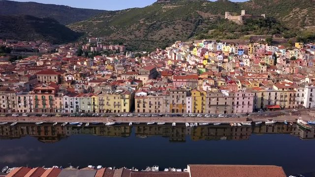 Bosa, Sardinia, Italy - Drone aerial shot moving leftwards over the river Temo in front of the colourful town of Bosa