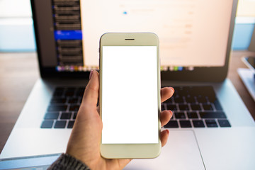 Closely business woman holding smartphone with empty mockup screen background with copy space for advertising text message against open laptop computer with blurred web site on the screen