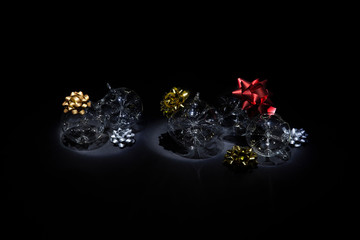 Transparent glass Christmas balls with colorful ribbons on black background