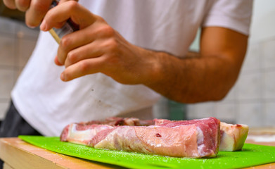 man putting spices on raw meat