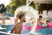 Bearded man with dreadlocks splashing water in pool