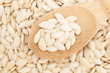 Pumpkin seeds and wooden spoon close up