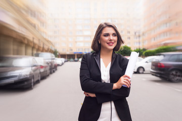 Beautiful  business woman in suit with folder of documents in her hands outdoors.