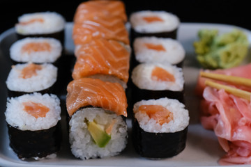 Sushi roll with seafood and soy sauce, wasabi and ginger. Sushi roll with salmon on a black...