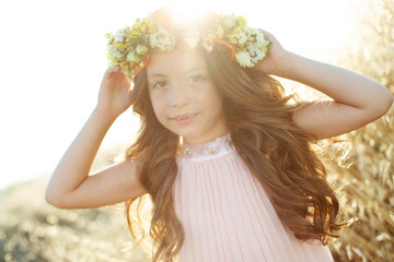 Naklejka premium Little girl with a wreath and flowers on her head. 