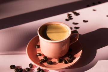 Coral colored cup with effuse coffee's beans with shadows on pastel rose background. Flat lay. Top view. Coffee concept. Pop art still life