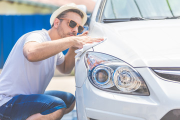 Modern young man cleaning car with cloth, car maintenance concept.